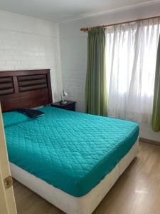 a bedroom with a bed with a green comforter at Casa la Serena Puertas del mar in La Serena
