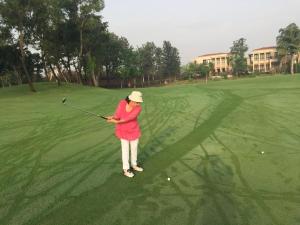 Eine Frau, die Golf auf einem Golfplatz spielt. in der Unterkunft STUDIO APARTMENT - TARUDHAN VALLEY GOLF RESORT Gurgaon in Gurgaon