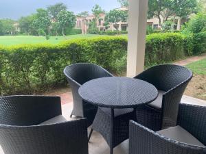 eine Terrasse mit einem Tisch und Stühlen sowie einem Golfplatz in der Unterkunft STUDIO APARTMENT - TARUDHAN VALLEY GOLF RESORT Gurgaon in Gurgaon