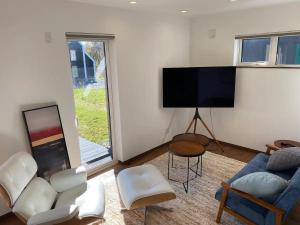 a living room with a couch and a flat screen tv at Niseko Forest Avenue 63 in Niseko