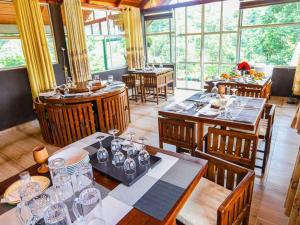 a dining room with tables and chairs and windows at 3Acres Sneha Villa in Haputale