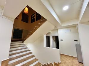 a staircase in a house with white walls and wooden floors at Apple Cherry Pine Green Homestay in Shillong
