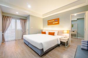 曼那Koon Hotel Sukhumvit的卧室里有一张白色的大床和一张书桌