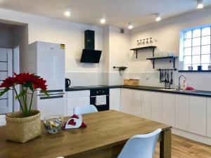 Una cocina con una mesa de madera y gabinetes blancos. en Apartament Ryneczek Bieszczad, en Ustrzyki Dolne