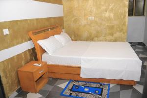 een kleine slaapkamer met een bed en een nachtkastje bij Afrika Nomades in Abidjan