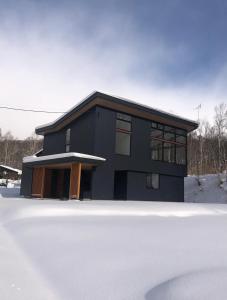 ein schwarzes Haus mit Schnee davor in der Unterkunft Niseko Kizuna Lodge in Niseko