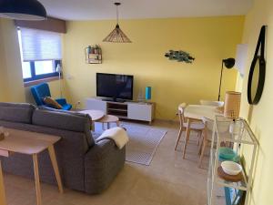 a living room with a couch and a table and a tv at Acogedor apartamento con terraza in Cedeira