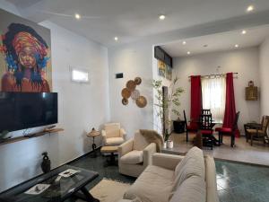 a living room with a couch and a flat screen tv at VILLA "MYKONOS" pour vos moments de détente en famille piscine privative, 3 chambre climatisées, salon climatise télé machine a laver cuisine, jardin arbore gardien parking 100 m de la plage in Ngaparou