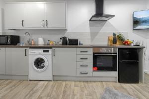 Una cocina con gabinetes blancos y lavadora y secadora. en City Centre Studio Apartments - Riley Apartment - Short Stays UK Ltd, en Exeter