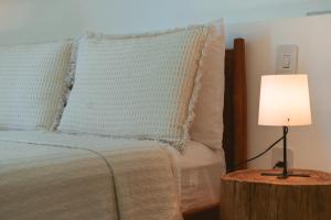 a bed with blue pillows and a lamp on a table at Conforto e Charme, Casa a 360m da Areia in Porto Seguro
