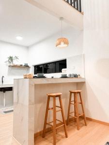 a kitchen with two wooden stools at a counter at Eastcape by The White Sands Homestay in Pekan
