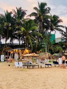 a beach with chairs and umbrellas and palm trees at Sunset Haven in Habaraduwa Central