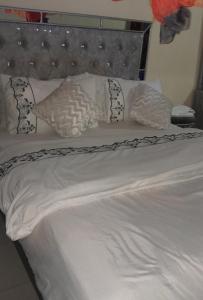 a bed with white sheets and pillows on it at Riverside apartment in Nairobi