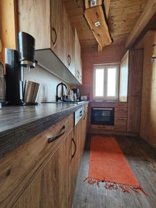 une cuisine avec des placards en bois et un tapis orange dans l'établissement Wellnesshütte Klippitztörl, à Klippitztorl
