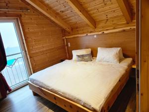 Ce lit se trouve dans une chambre en bois dotée d'une grande fenêtre. dans l'établissement Wellnesshütte Klippitztörl, à Klippitztorl