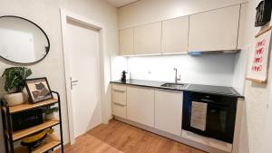 克莱恩 蒙塔纳Grand studio au cœur de Crans et au pied des pistes的厨房配有白色橱柜、水槽和镜子 更多6张照片