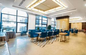 a dining room with blue chairs and tables and windows at Emaar International in Mecca