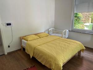 a bedroom with a bed with a yellow comforter and a window at Studio - simply living in Antwerp