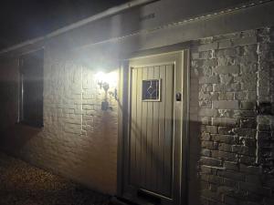 a door with a light next to a brick wall at The White Bungalow in Boughton