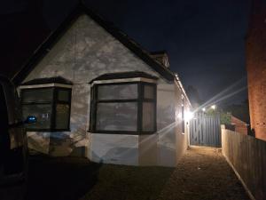 a house with a light on the side of it at night at The White Bungalow in Boughton