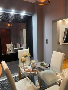 a dining room with a glass table and white chairs at Maria's luxury apartment in Athens