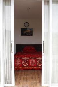 a bedroom with a red bed with a clock on the wall at Rumah Marmut Pakancilan in Tagalbato +15 photos