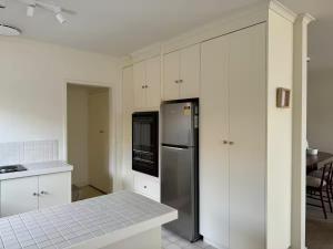 a kitchen with white cabinets and a stainless steel refrigerator at Interior Stylist's Country Unit in Nhill