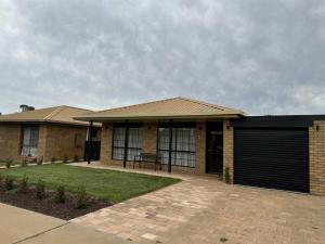 a brick house with a gate and a garage at Interior Stylist's Country Unit in Nhill