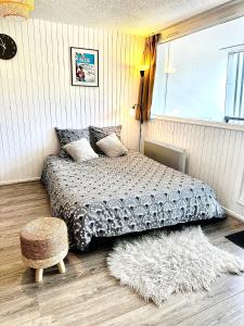 sypialnia z łóżkiem z dywanem i stołkiem w obiekcie Appartement cosy Centre station de Super Besse pour 2 à 6 personnes w mieście Besse-et-Saint-Anastaise