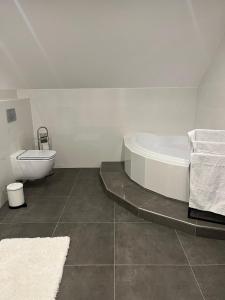 a white bathroom with a tub and a toilet at B-Willa Słopnice basen & jacuzzi, sauna in Słopnice +51 photos