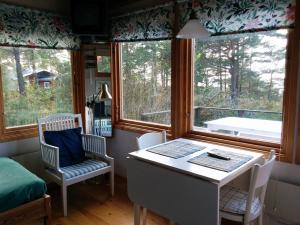 a room with a table and chairs and windows at Liten stuga med havsutsikt in VBY +12 photos