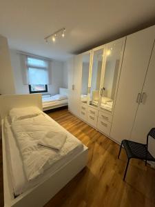 Un dormitorio blanco con una cama y un espejo. en Best Frankfurt Apartments, en Frankfurt