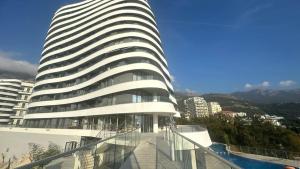 a large white building with a pool in front of it at Панорамная квартира на первой линии моря Skyline Resort, Becici, Budva in Becici