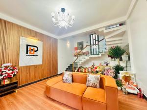 a living room with an orange couch and a staircase at PU Homestay in Hue