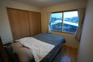 a small bedroom with a bed and a window at エル白馬 L hakuba in Hakuba