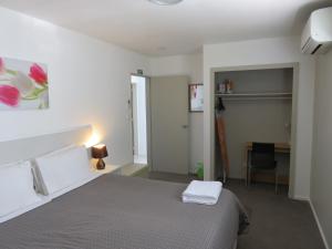 a bedroom with a bed and a desk with a chair at McWilliam Apartments in Christchurch