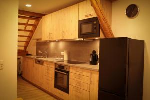 a kitchen with a black refrigerator and wooden cabinets at Ferienwohnung Bauernhaus 3 in Balingen