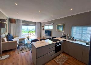 a kitchen and living room with a couch and a table at Mouille Point Seafront Cottage in Cape Town