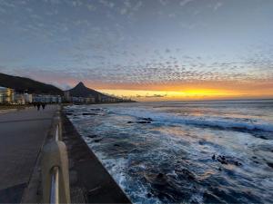 a view of the beach at sunset at Mouille Point Seafront Cottage in Cape Town
