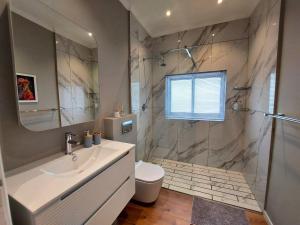 a bathroom with a sink and a shower at Mouille Point Seafront Cottage in Cape Town