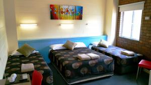 Habitación con 2 camas, mesa y sillas en A&A Lodge Motel, en Emerald