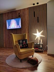 a living room with a yellow chair and a television at Mieszkanie nad Jeziorem Rożnowskim in Rożnów