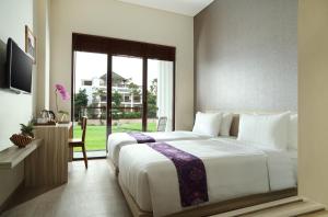 a bedroom with a large white bed and a window at The Evitel Resort Ubud in Ubud