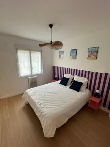 a bedroom with a large white bed with blue stripes at Appartement rez-de-chaussée de chaussée entre ville et plage in Dunkerque