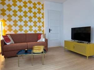 a living room with a couch and a tv at Appartement rez-de-chaussée de chaussée entre ville et plage in Dunkerque