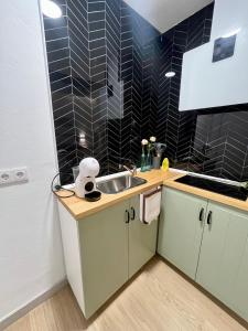 a kitchen with a sink and a black tiled wall at Apartamentos Rey 2 in Prado del Rey +2 photos