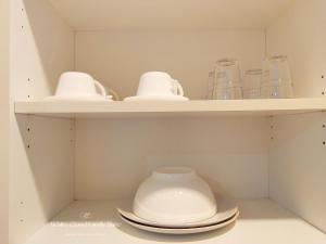 a shelf with cups and bowls and plates on it at White Cloud Family Suite in Hat Yai