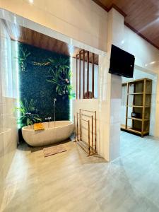 a bathroom with a tub with plants on the wall at Ayu Homestay in Ubud