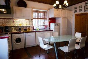 a kitchen with a glass table and white chairs at Casa Villa Garden in Ponta Delgada