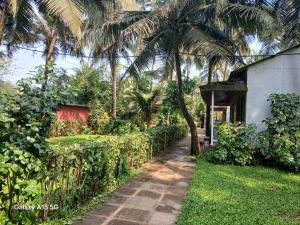 a walkway in front of a house with palm trees at Furtado's Beach Resort in Benaulim